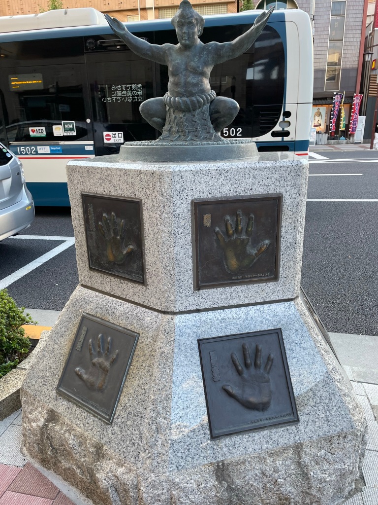 monument with bronze sumo wrestler and sumo handprints. 